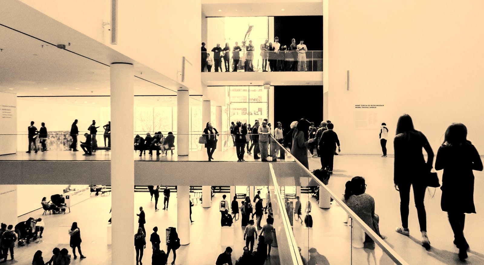 A dynamic black and white image of people in a modern museum setting.