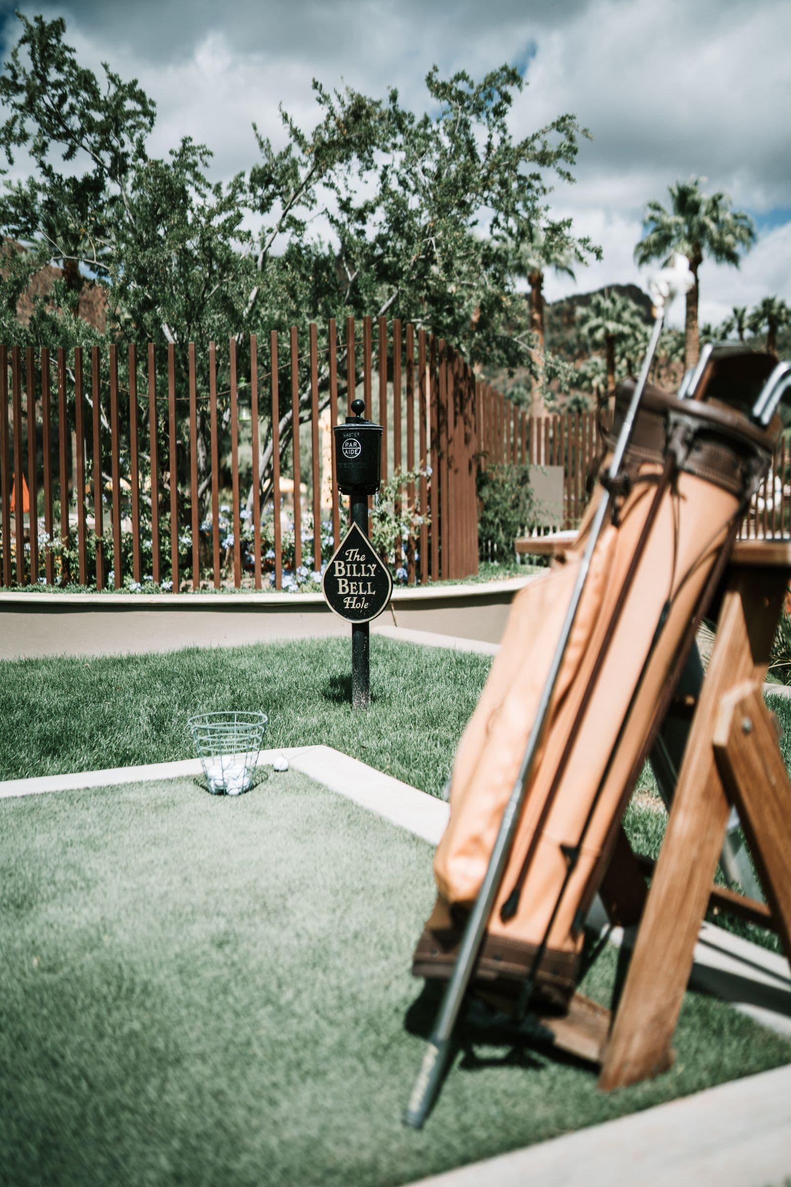 Tan leather golf bag on a stand beside a basket of balls at an upscale course