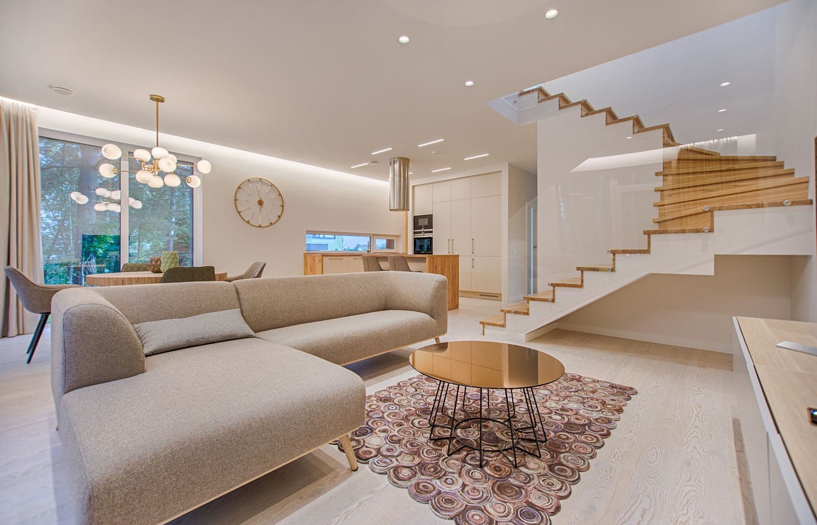 Bright modern living room with a light sectional, round coffee table, and open plan beyond