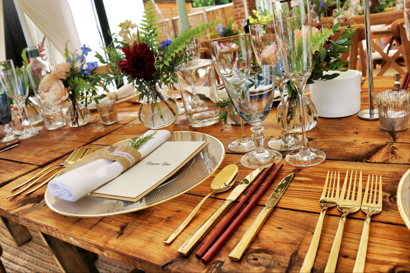 Gold flatware and linen napkin with rosemary on a rustic wooden table
