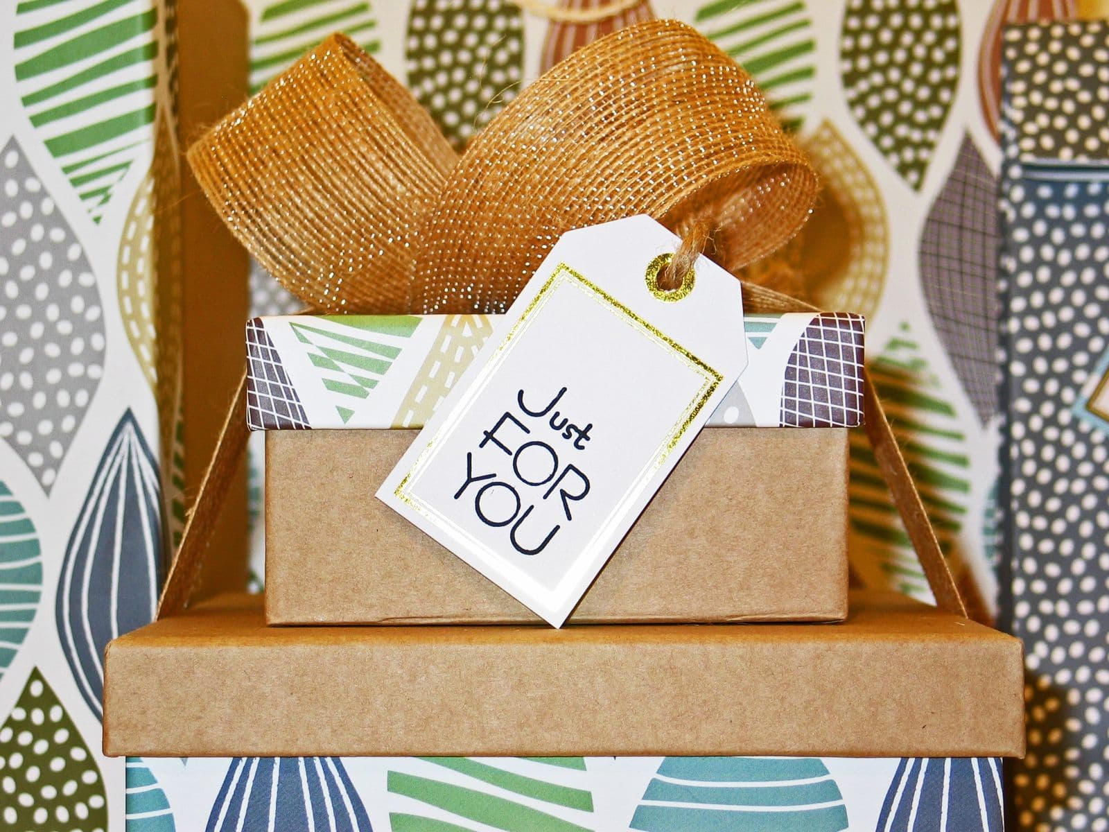 Stacked gift boxes with patterned lids, gold ribbon, and a Just For You tag