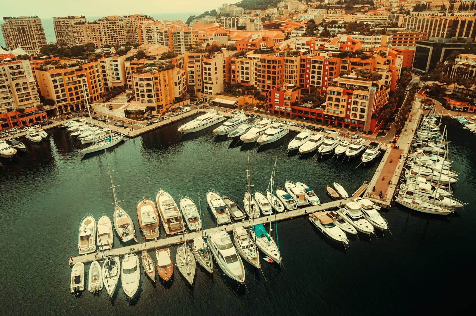 Aerial shot of a yacht marina surrounded by urban buildings in Monaco, showcasing luxury waterfront.