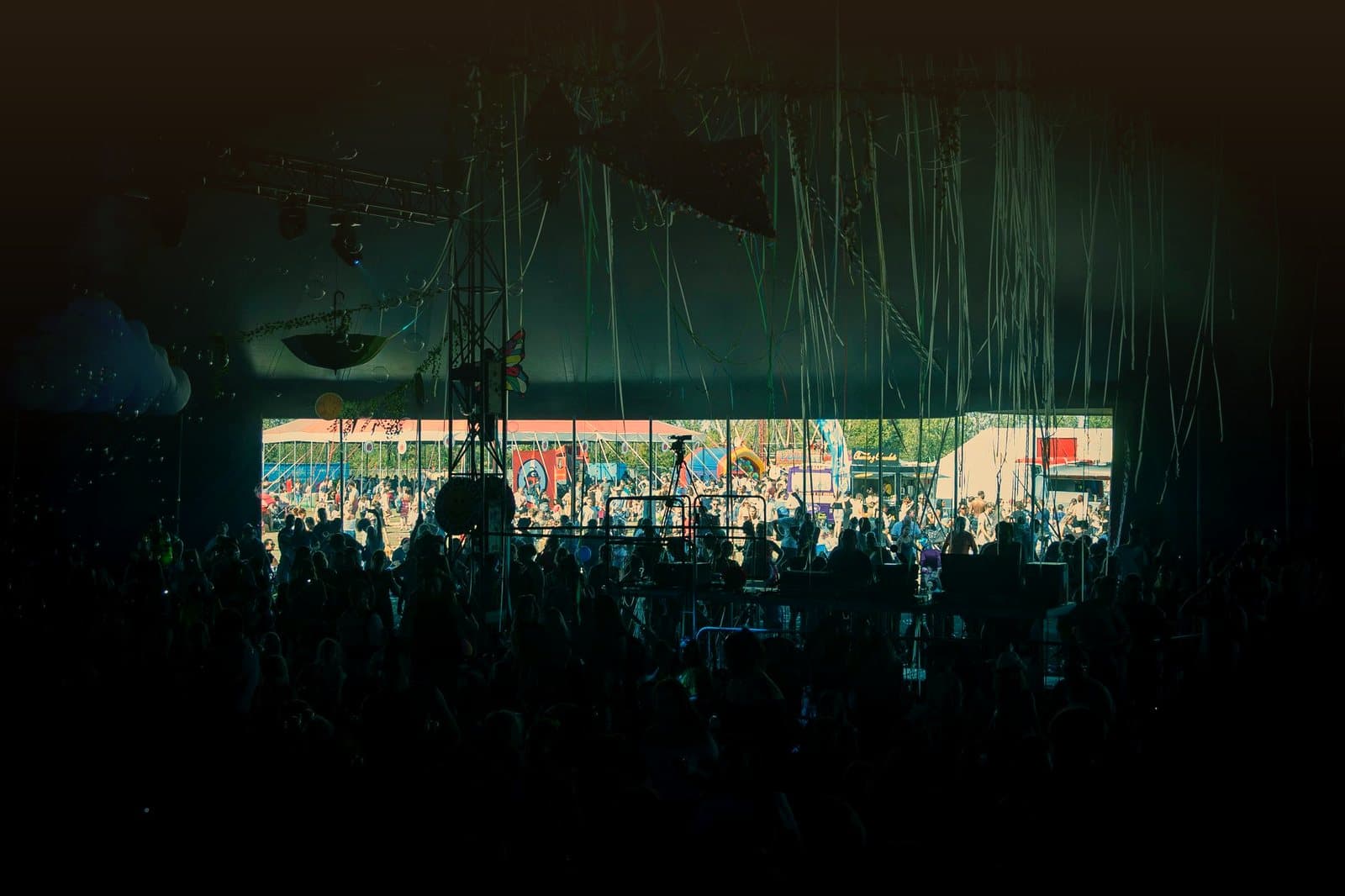 A crowd enjoying live music at a colorful outdoor festival stage.