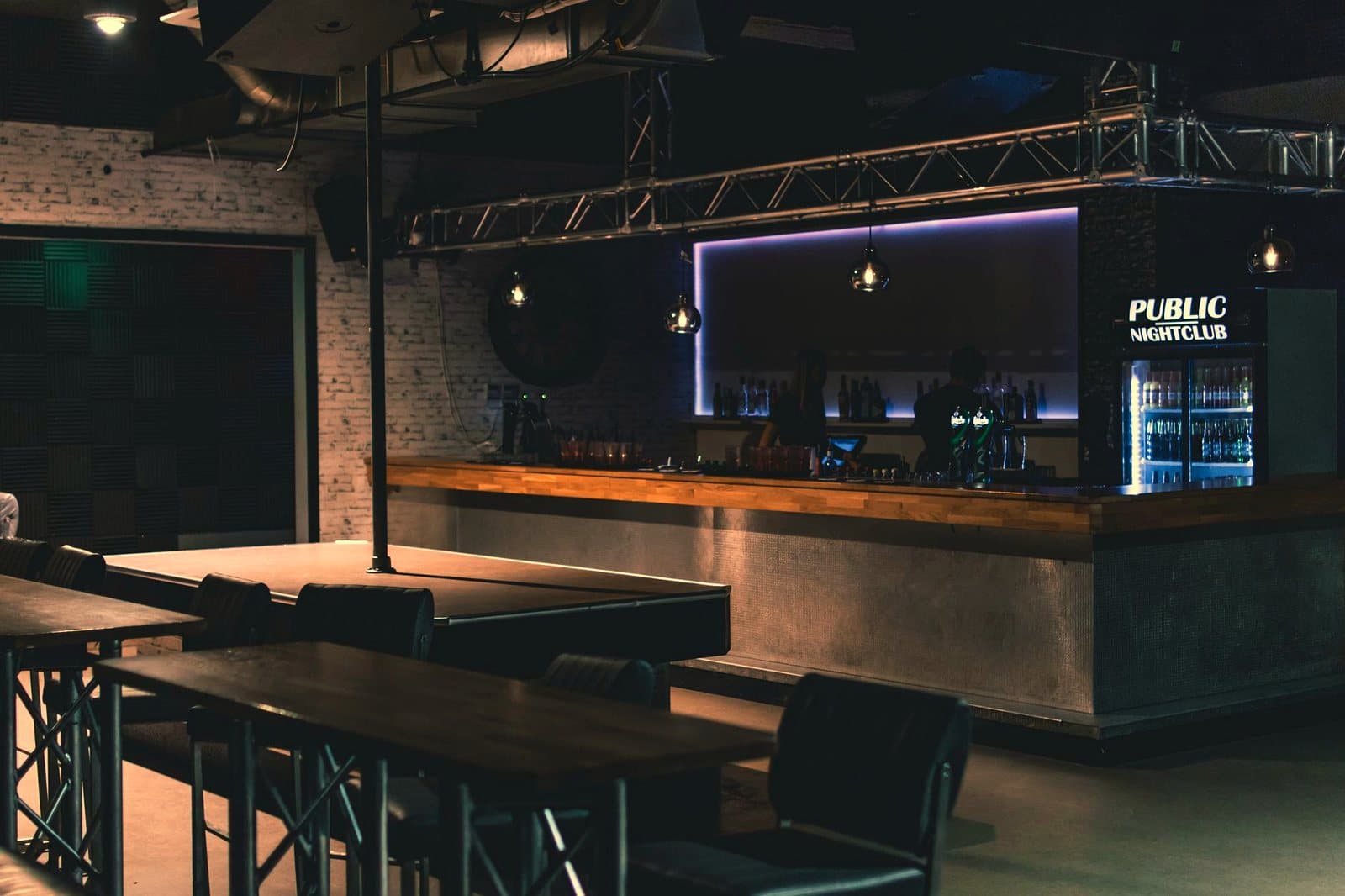 Stylish modern nightclub interior featuring a sleek bar counter with ambient lighting and industrial design elements.