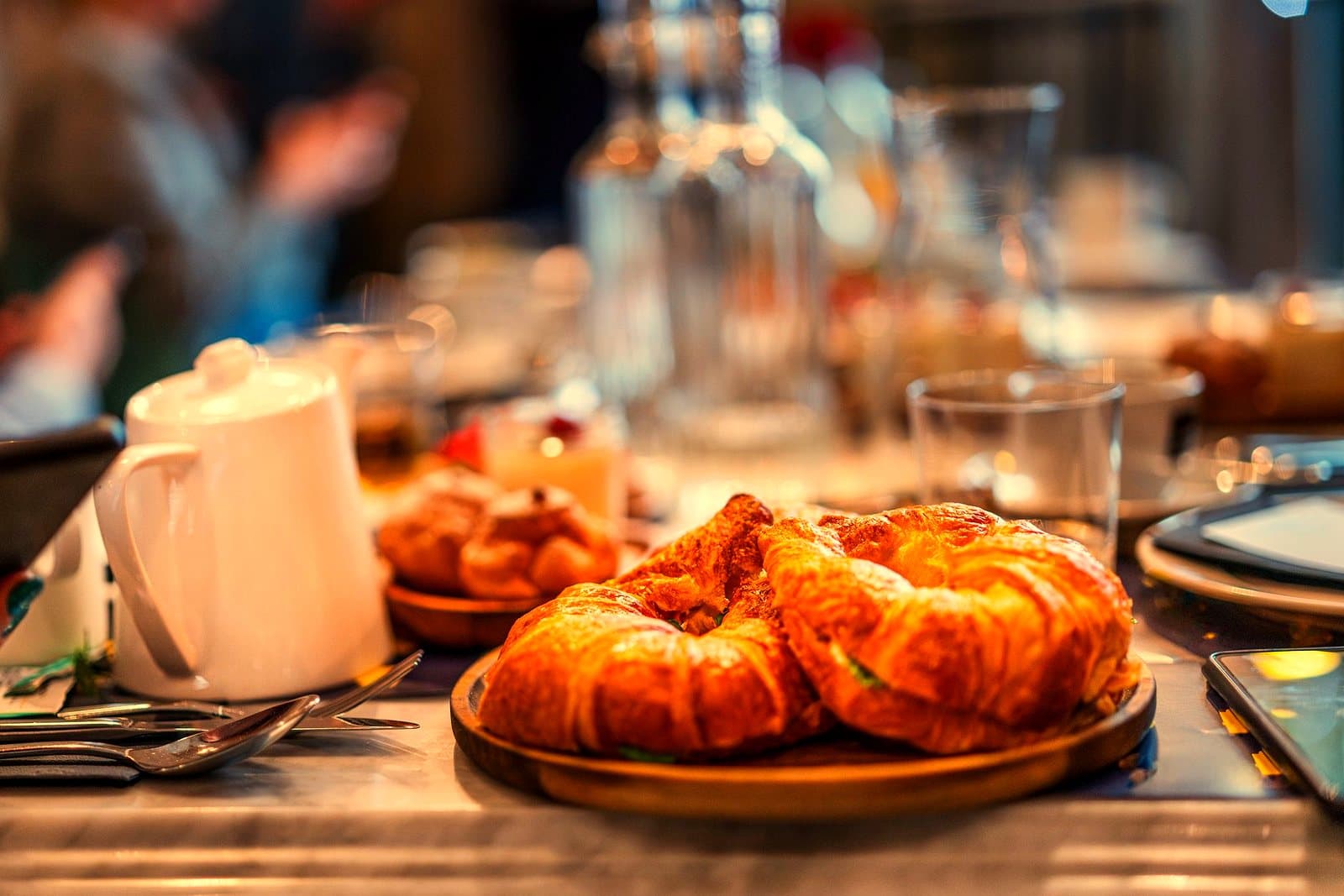 Close-up of croissants on a café table with elegant dining setting, perfect for breakfast.