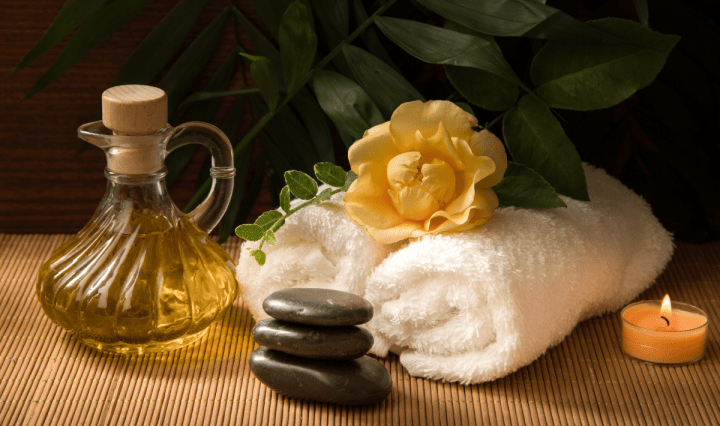 spa accessories with towels, stones, oil, and candle